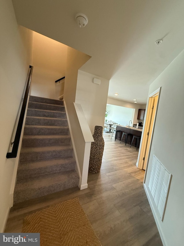 stairway with recessed lighting, baseboards, visible vents, and wood finished floors