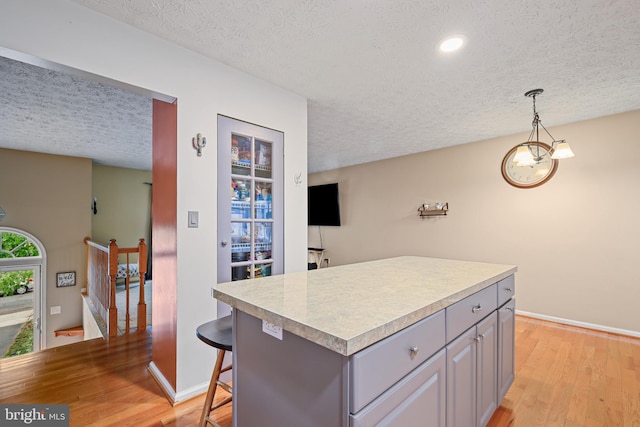 7815 Shallowbrook Ct, Severn, MD 21144 - kitchen with a textured ceiling, light countertops, gray cabinetry, baseboards, and light wood-style floors