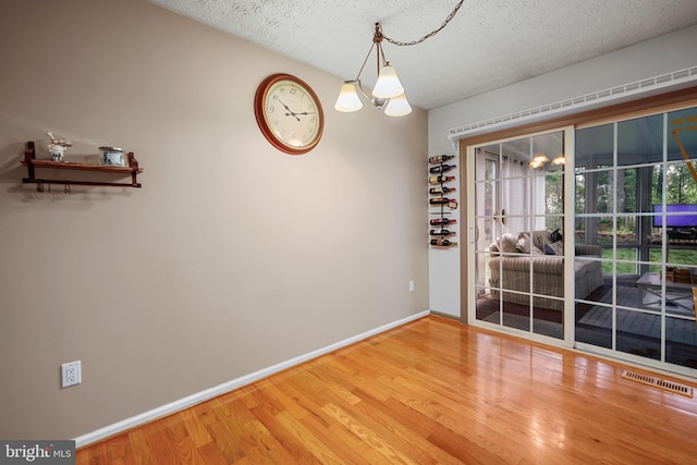 7815 Shallowbrook Ct, Severn, MD 21144 - unfurnished dining area with a textured ceiling, visible vents, wood finished floors, and a notable chandelier