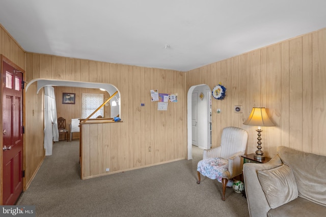 sitting room featuring arched walkways, carpet floors, and wooden walls