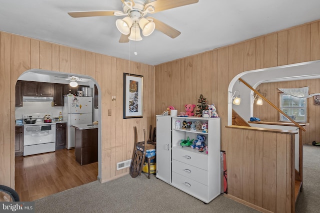 bedroom featuring arched walkways, carpet, wooden walls, and freestanding refrigerator