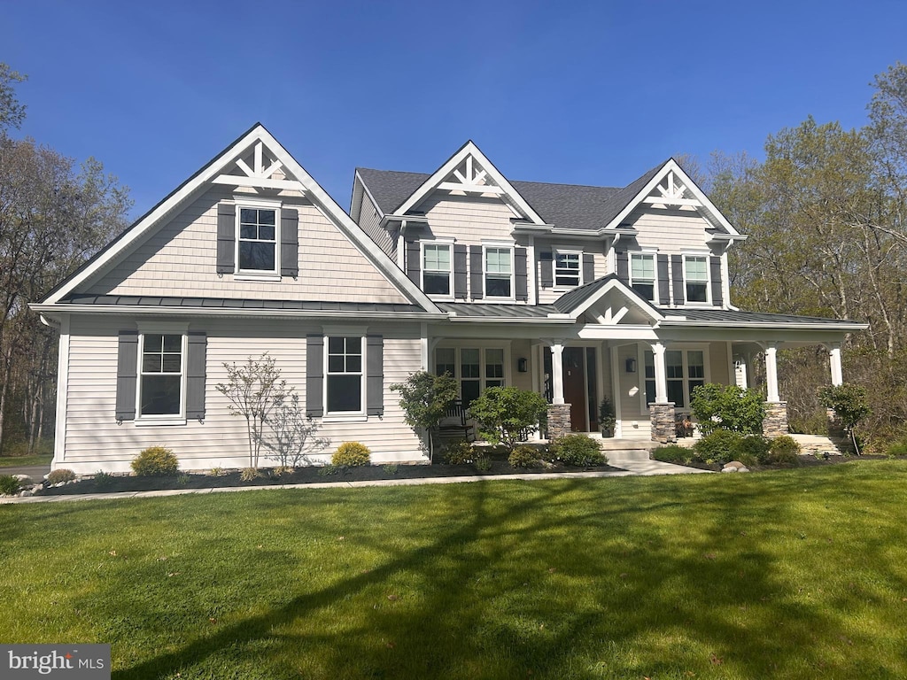 craftsman inspired home with a standing seam roof, a porch, and a front yard