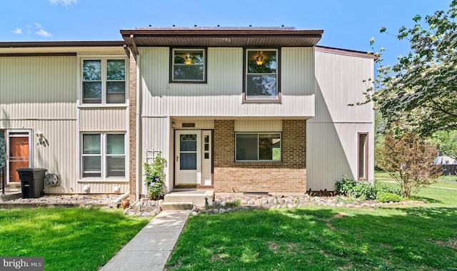multi unit property with brick siding and a front yard