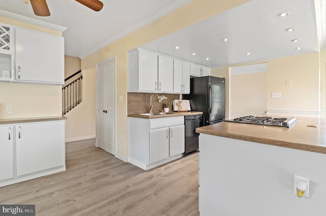kitchen with light wood-type flooring, a sink, white cabinets, and black appliances