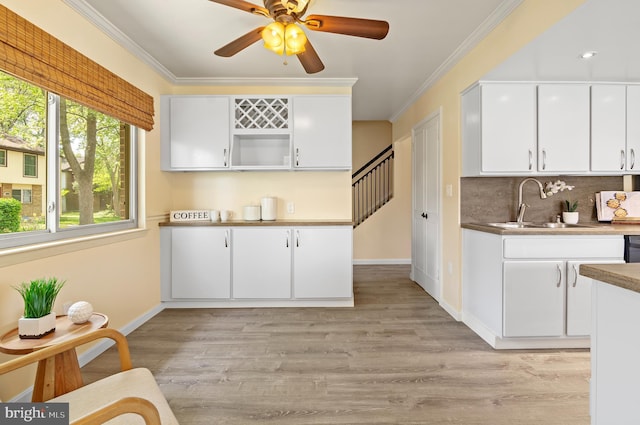 kitchen featuring backsplash, white cabinetry, baseboards, and a sink