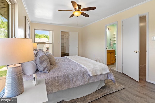 bedroom featuring crown molding, visible vents, wood finished floors, connected bathroom, and a spacious closet