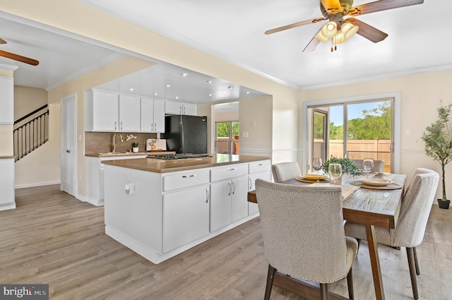 kitchen featuring freestanding refrigerator, a ceiling fan, ornamental molding, and a kitchen island