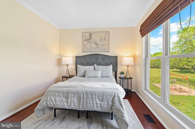 bedroom featuring crown molding, baseboards, wood finished floors, and visible vents