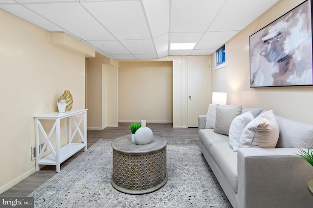 living area featuring baseboards, a drop ceiling, and wood finished floors