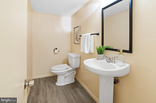bathroom with baseboards, toilet, and wood finished floors