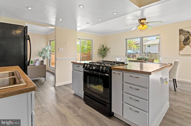 kitchen featuring crown molding, wooden counters, a ceiling fan, light wood-type flooring, and black appliances