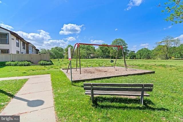 view of home's community featuring a lawn, fence, and playground community