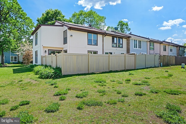 back of property with fence and a yard