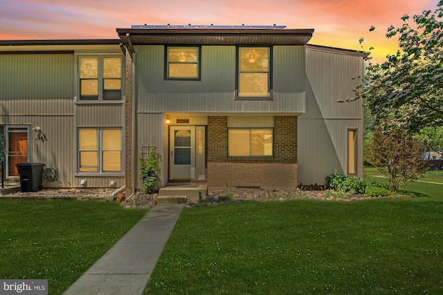 view of front of house with a lawn and brick siding