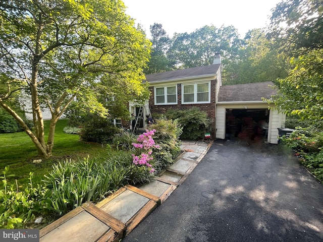 view of front of home featuring a garage, a chimney, driveway, and brick siding