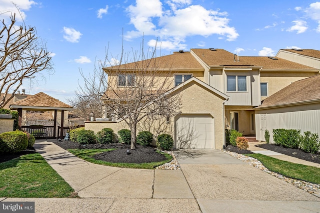 multi unit property featuring a gazebo, a garage, stucco siding, and concrete driveway