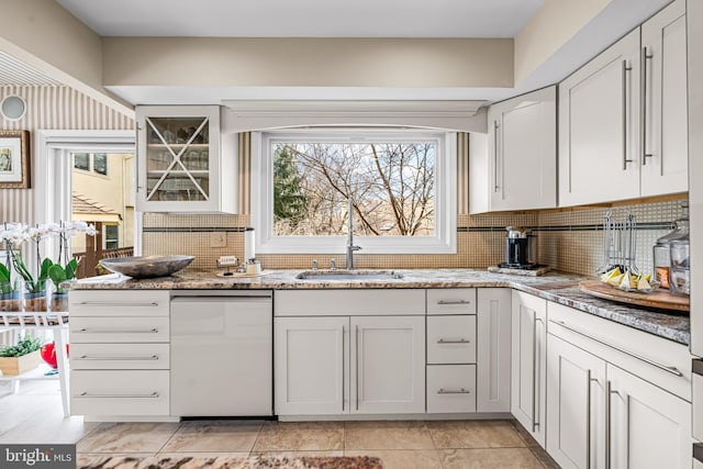 kitchen with a sink, white cabinets, light stone countertops, and tasteful backsplash