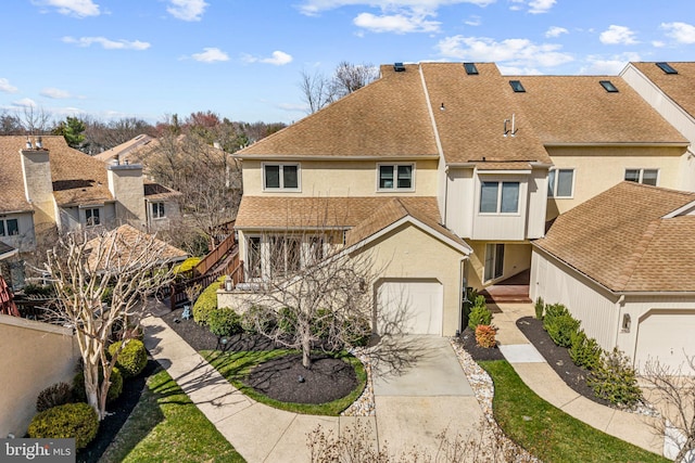 multi unit property with roof with shingles, a residential view, a garage, concrete driveway, and stucco siding