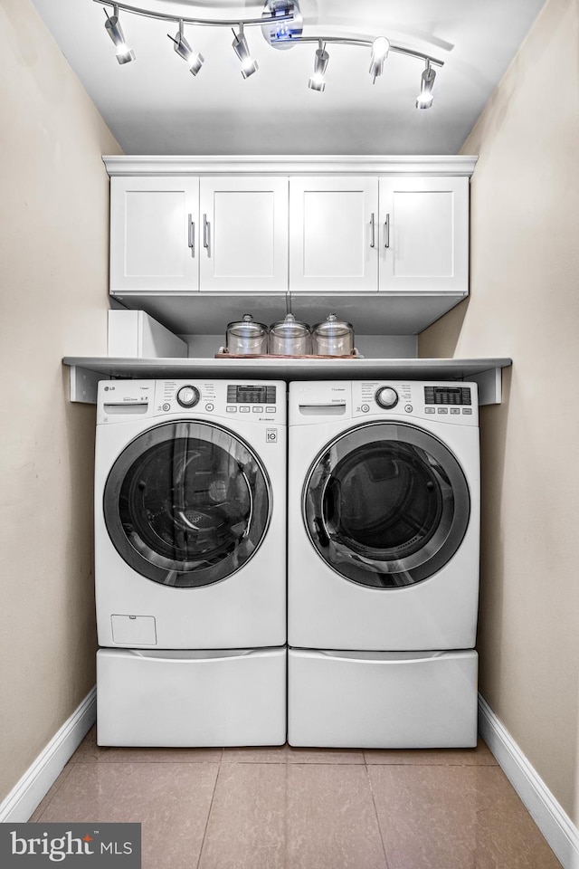 laundry room featuring cabinet space, baseboards, tile patterned floors, and washing machine and clothes dryer