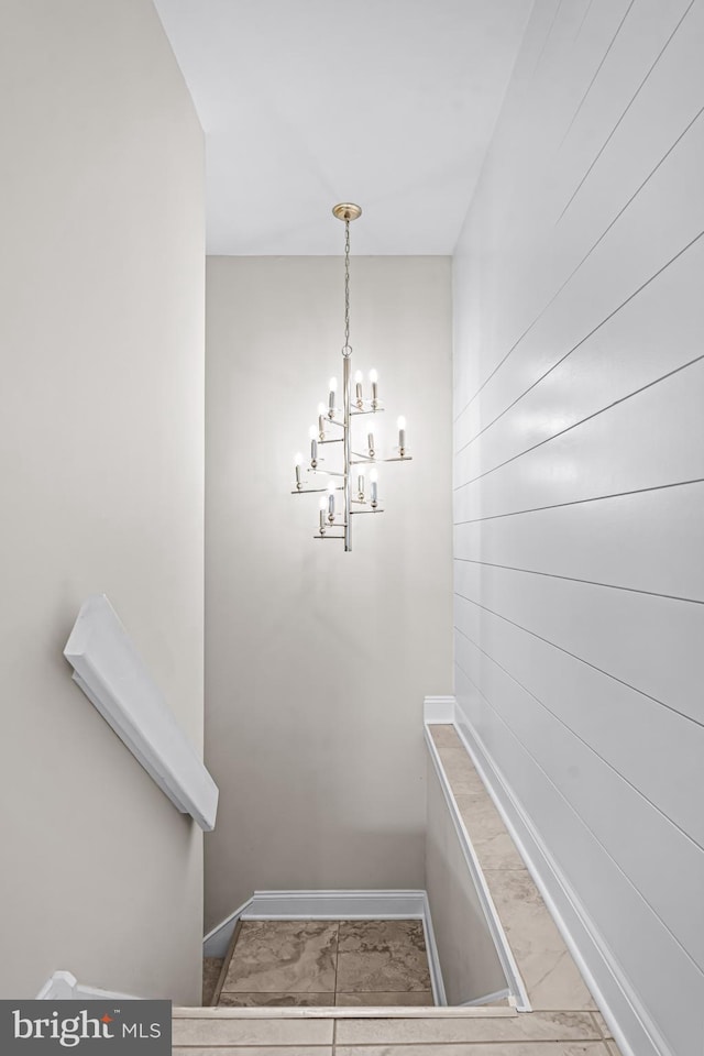 stairs featuring baseboards, marble finish floor, and a notable chandelier