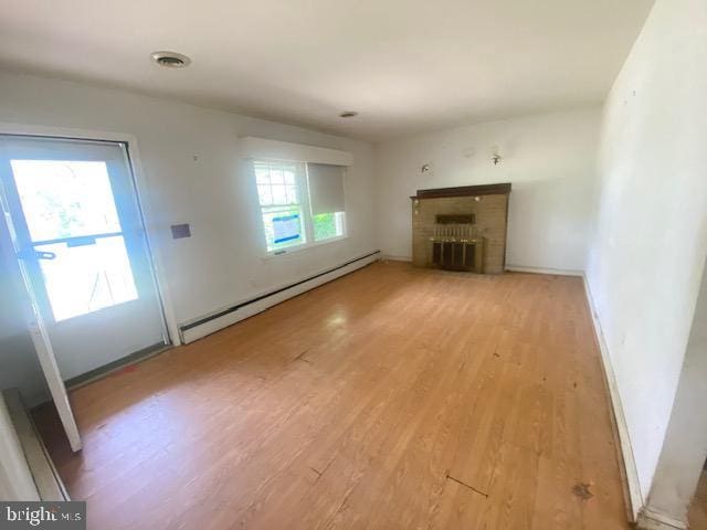 unfurnished living room featuring visible vents, a brick fireplace, baseboards, a baseboard heating unit, and light wood-style floors