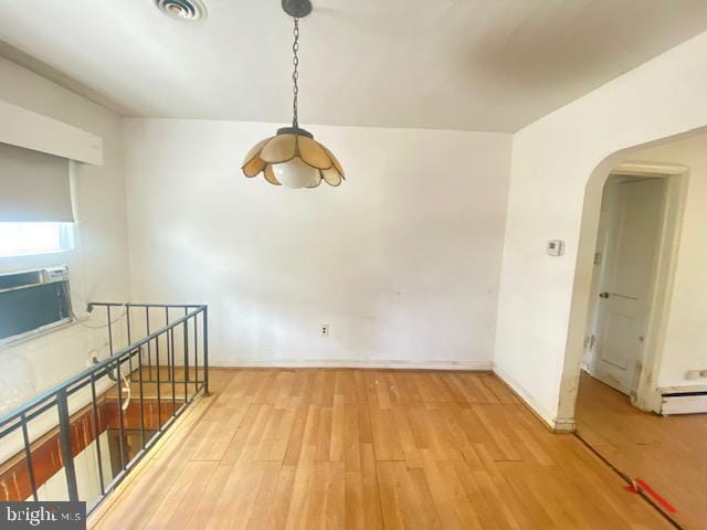 unfurnished room with visible vents, arched walkways, baseboards, and wood finished floors