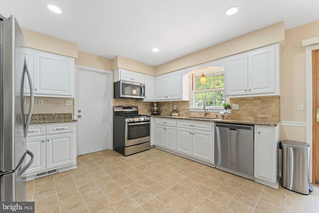 kitchen featuring appliances with stainless steel finishes, white cabinets, and backsplash