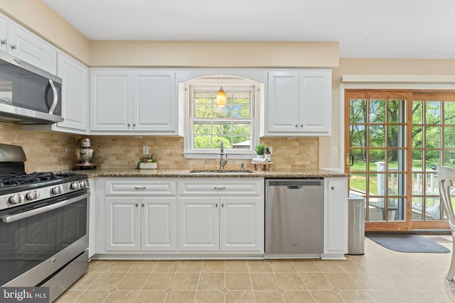 kitchen with appliances with stainless steel finishes, tasteful backsplash, a sink, light stone counters, and white cabinetry