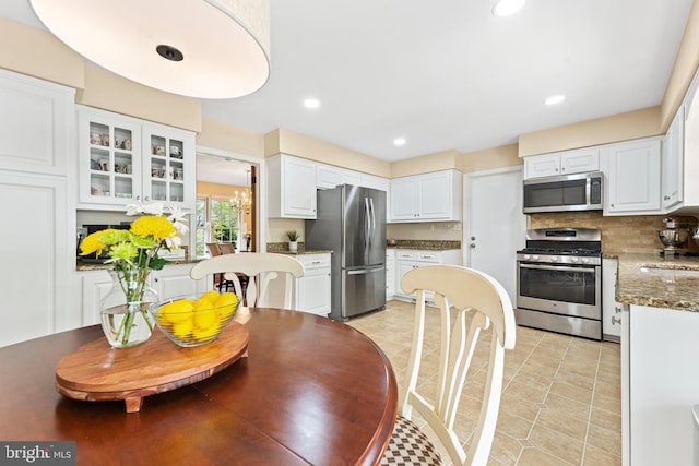 kitchen with decorative backsplash, glass insert cabinets, recessed lighting, white cabinets, and appliances with stainless steel finishes