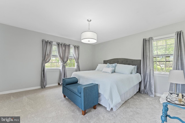bedroom with baseboards, multiple windows, and light carpet