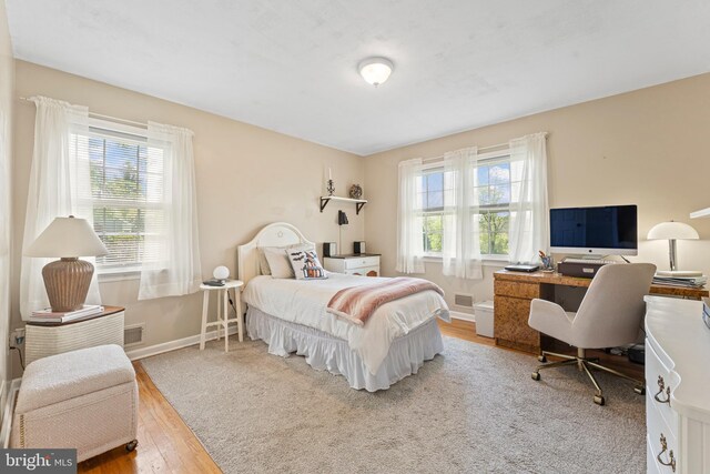 bedroom featuring baseboards, wood finished floors, and visible vents
