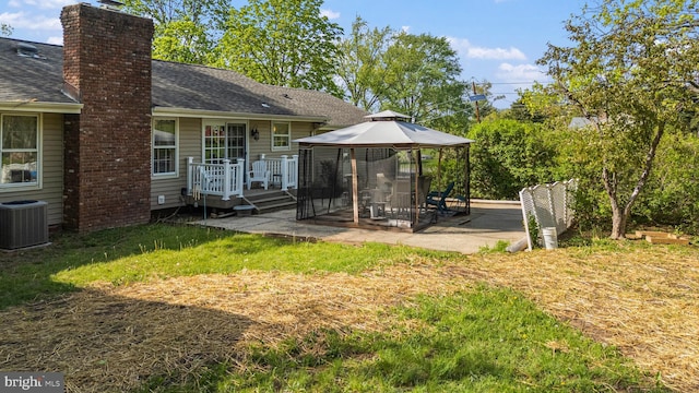 rear view of house with a shingled roof, a gazebo, a chimney, cooling unit, and a patio