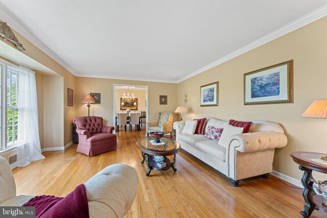 living area featuring an inviting chandelier, ornamental molding, baseboards, and wood finished floors