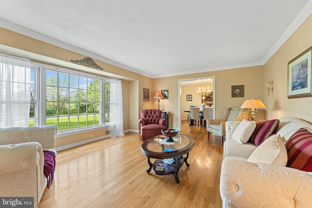 living room with baseboards, ornamental molding, light wood-style flooring, and a notable chandelier
