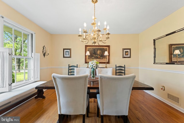 dining room with visible vents, plenty of natural light, wood finished floors, and an inviting chandelier
