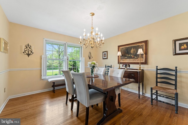 dining space with an inviting chandelier, baseboards, and wood finished floors