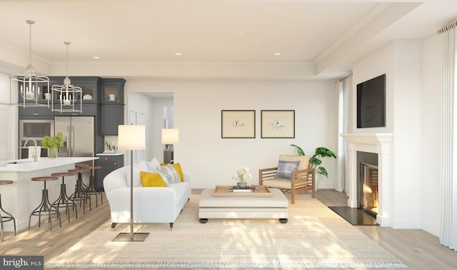 living room with a fireplace with flush hearth, ornamental molding, light wood-style flooring, and a notable chandelier