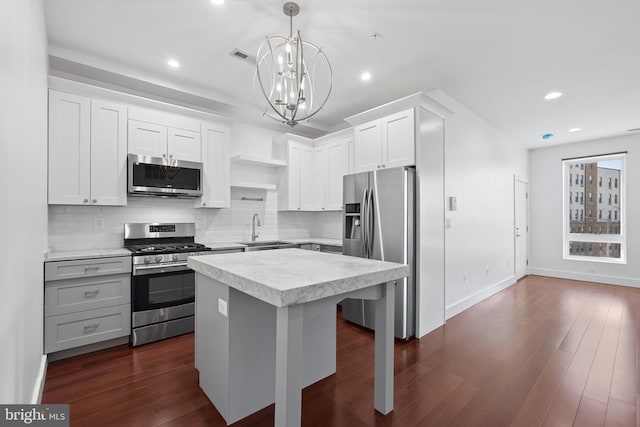 kitchen featuring appliances with stainless steel finishes, open shelves, a sink, light countertops, and a notable chandelier