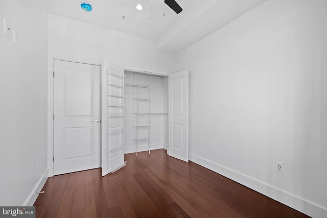 unfurnished bedroom with dark wood-style flooring, baseboards, ceiling fan, and a closet