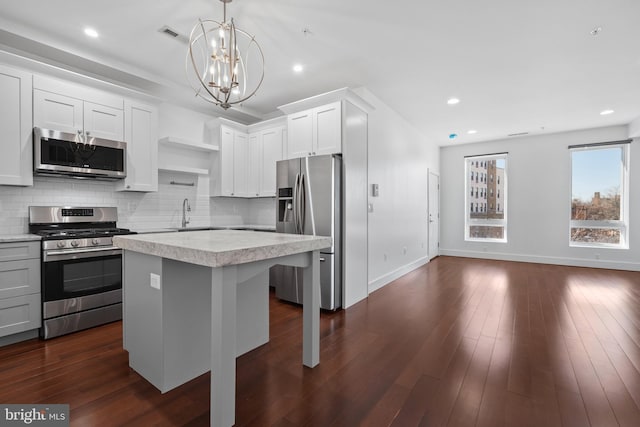kitchen featuring backsplash, light countertops, baseboards, a notable chandelier, and stainless steel appliances