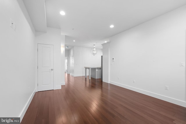 unfurnished living room featuring dark wood-type flooring, recessed lighting, and baseboards