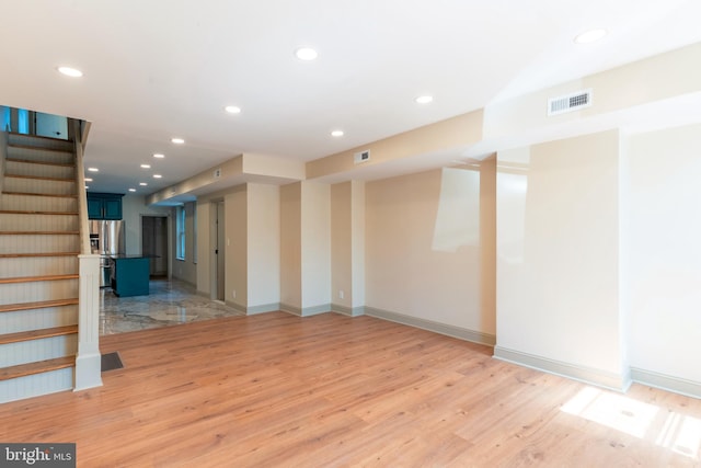unfurnished room with visible vents, stairway, and light wood-style floors
