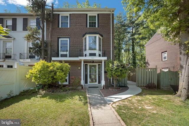 multi unit property featuring brick siding, fence, and a front yard