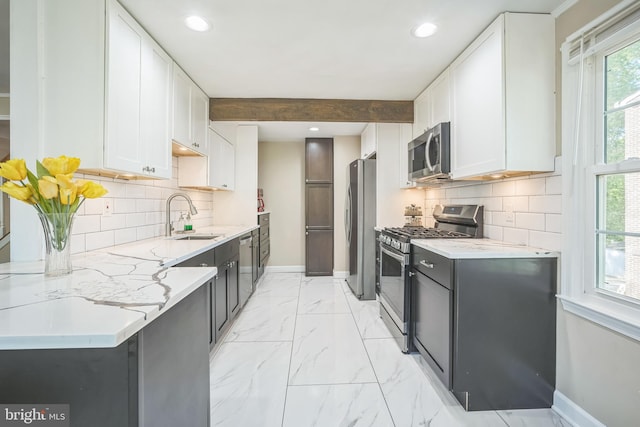 kitchen featuring stainless steel appliances, baseboards, white cabinetry, and a sink