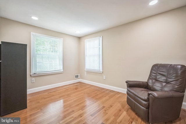 sitting room featuring visible vents, light wood-style flooring, and baseboards