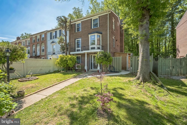 back of house featuring brick siding, a lawn, and fence