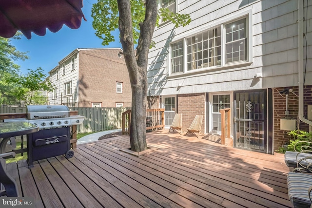 wooden terrace featuring fence and a grill