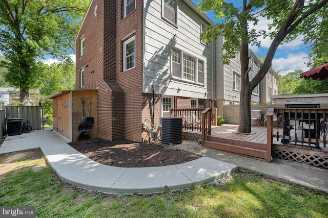 back of house featuring brick siding, central AC unit, and a wooden deck