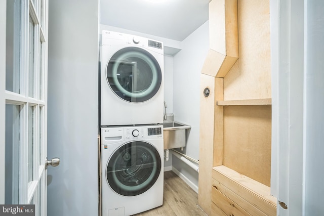 washroom with baseboards, stacked washer and clothes dryer, wood finished floors, and laundry area