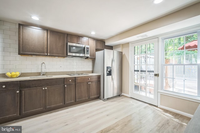 kitchen with light wood-style floors, a sink, dark brown cabinetry, and stainless steel appliances